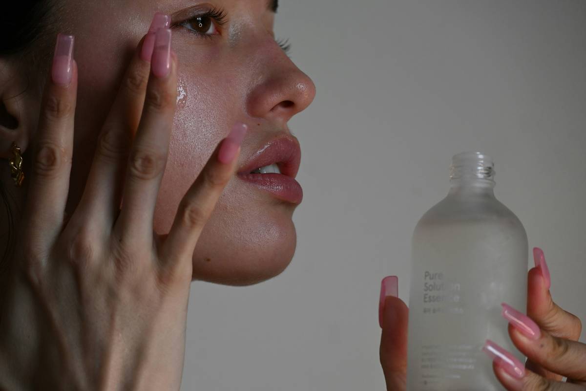 Woman applying hydrating cream moisturizer can body lotion to her arms after a shower